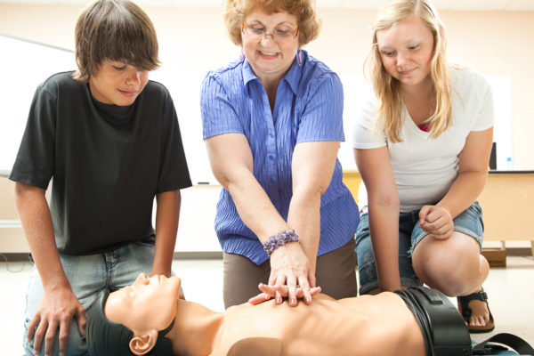 Teacher demonstrates CPR life saving techniques for her teenage students.