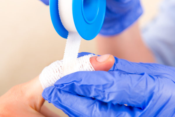Hands in blue gloves s putting bandage on a finger